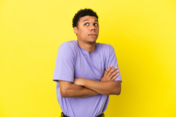 Young African American man isolated on yellow background making doubts gesture while lifting the shoulders