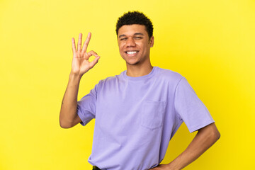Young African American man isolated on yellow background showing ok sign with fingers
