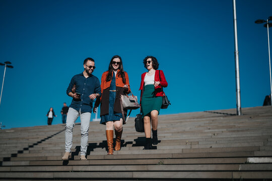 Image of three professionals, in casual business attire, walking down the stairs after a successful team meeting. - Powered by Adobe