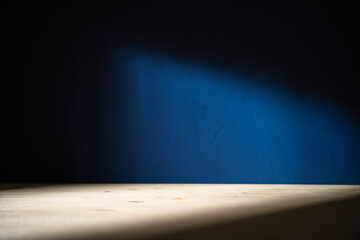 Table on dark blue wall background. Minimalist composition with abstract shadow on the wall and...