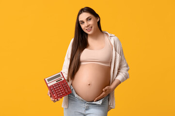 Pregnant young woman with calculator on yellow background