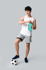 Sporty guy with bottle of water and football ball on white background