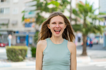 Young blonde woman with glasses at outdoors with surprise facial expression