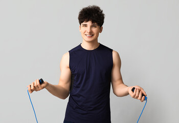 Sporty guy with jumping rope on white background