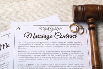 Marriage contract, golden wedding rings and gavel on wooden table