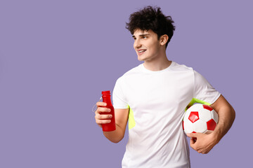 Sporty guy with bottle of water and football ball on lilac background