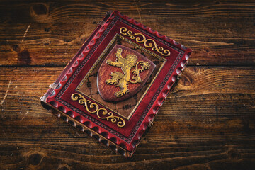 Aged leather book with the lion on the front cover plate lay down to old wooden table.