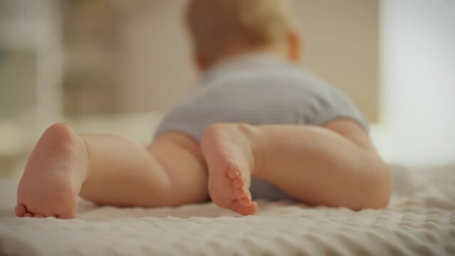 Close-up of a small child's feet. The child lies on his tummy and kicks his little legs. Physical development of a small child in the first months after birth. The process of mastering leg movements