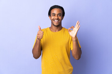 Young African American man with braids man isolated on purple background showing ok sign and thumb...