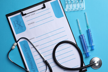 Clipboard with medical prescription form, stethoscope, ampoules and syringes on light blue background, flat lay