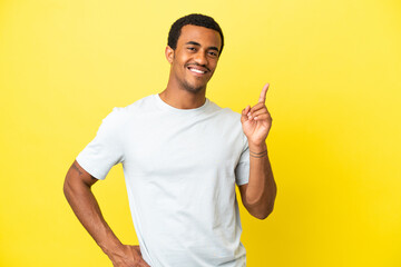 African American handsome man on isolated yellow background showing and lifting a finger in sign of...