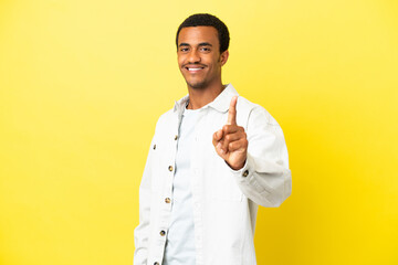 African American handsome man on isolated yellow background showing and lifting a finger