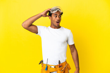 African American electrician man over isolated yellow wall doing surprise gesture while looking to...