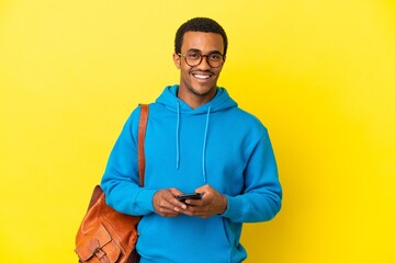 African American student man over isolated yellow background surprised and sending a message