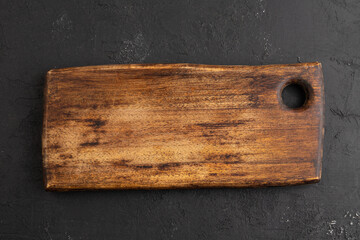 Empty rectangular wooden cutting board on black concrete. Top view