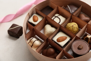 Box with delicious chocolate candies on white grunge background, closeup