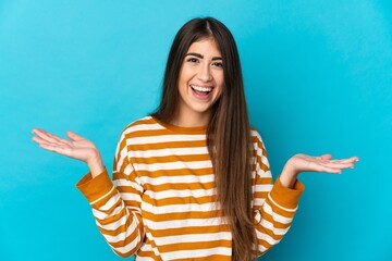 Young caucasian woman isolated on blue background with shocked facial expression