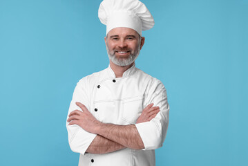 Happy chef in uniform on light blue background