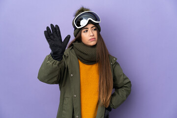 Skier caucasian girl with snowboarding glasses isolated on purple background making stop gesture and disappointed