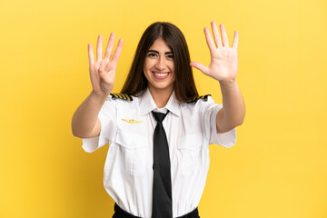 Airplane pilot isolated on yellow background counting nine with fingers