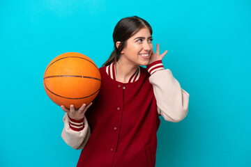 Young caucasian basketball player woman isolated on blue background listening to something by...