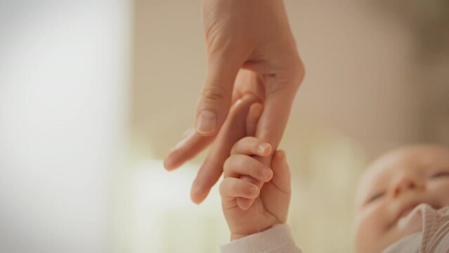The young mother's fingers gently hug her baby's hand, expressing endless care and tenderness. They radiate warmth and peace, creating an atmosphere of sincere love with them