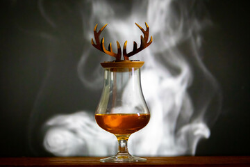 Single malt scotch whiskey in crystal glass with deer antler and smoke rustic background