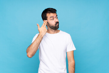 Young man with beard  over isolated blue background with problems making suicide gesture
