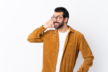 Caucasian handsome man with beard wearing a corduroy jacket over isolated white background listening to something by putting hand on the ear