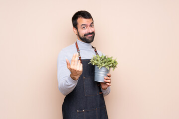 Man holding a plant over isolated background inviting to come with hand. Happy that you came