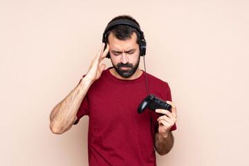 Man playing with a video game controller over isolated wall with headache