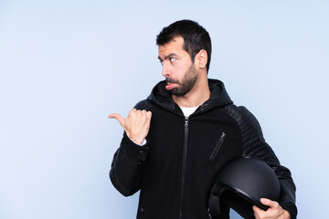 Man with a motorcycle helmet over isolated background unhappy and pointing to the side