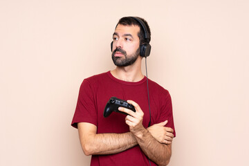 Man playing with a video game controller over isolated wall portrait