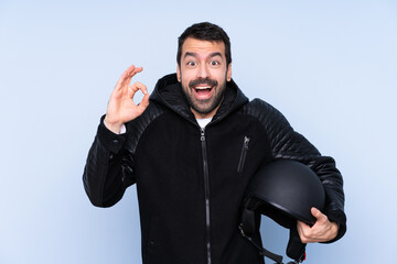 Man with a motorcycle helmet over isolated background surprised and showing ok sign