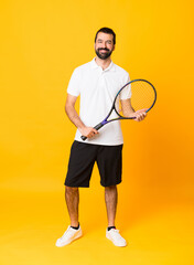 Full-length shot of man over isolated yellow background playing tennis