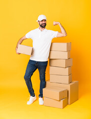 Full-length shot of delivery man among boxes over isolated yellow background doing strong gesture
