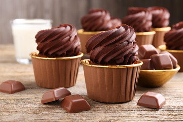 Delicious cupcakes and chocolate pieces on wooden table, closeup