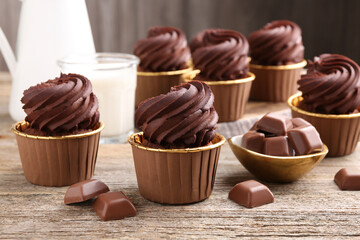 Delicious cupcakes and chocolate pieces on wooden table