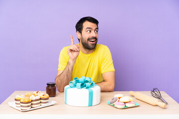 Man in a table with a big cake thinking an idea pointing the finger up