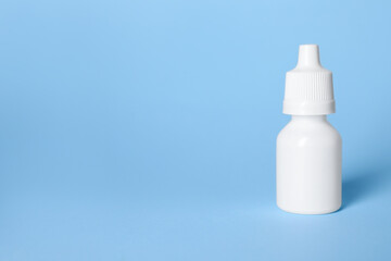 Bottle of medical drops on light blue background, space for text