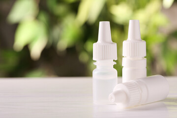 Bottles of medical drops on wooden table against blurred background, space for text