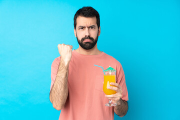 Young man over holding a cocktail over isolated blue background with angry gesture