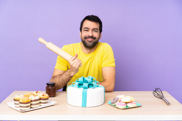 Man in a table with a big cake over purple backgroun