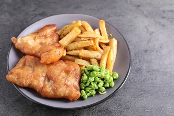 Tasty fish, chips and peas on grey table