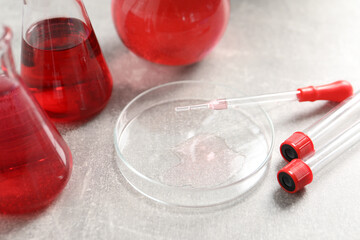 Laboratory analysis. Different glassware with red liquid on light grey table