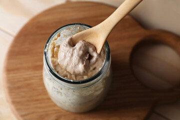 Taking sourdough starter with spoon at table, closeup