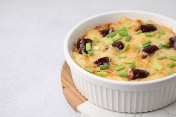 Tasty sausage casserole with green onions in baking dish on white table, closeup. Space for text