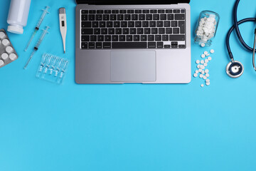 Flat lay composition with laptop and medical supplies on light blue background. Space for text