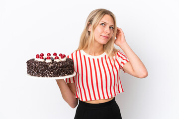 Young caucasian woman holding birthday cake isolated on white background having doubts