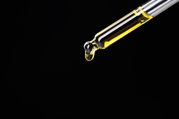 Dripping tincture from pipette on black background, closeup. Space for text